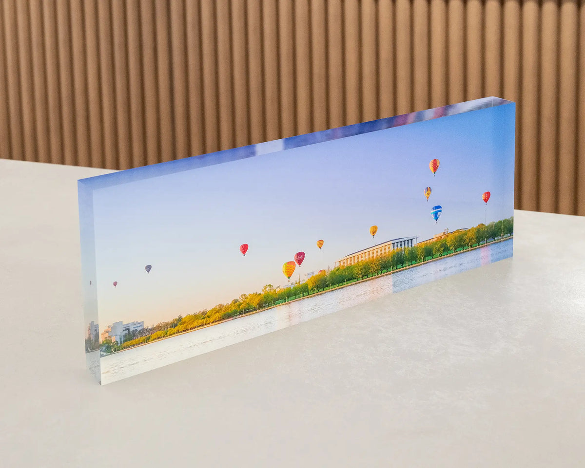 Upwards. Acrylic block, hot air balloons over National Library, during balloon spectacular festival, sitting on desk.