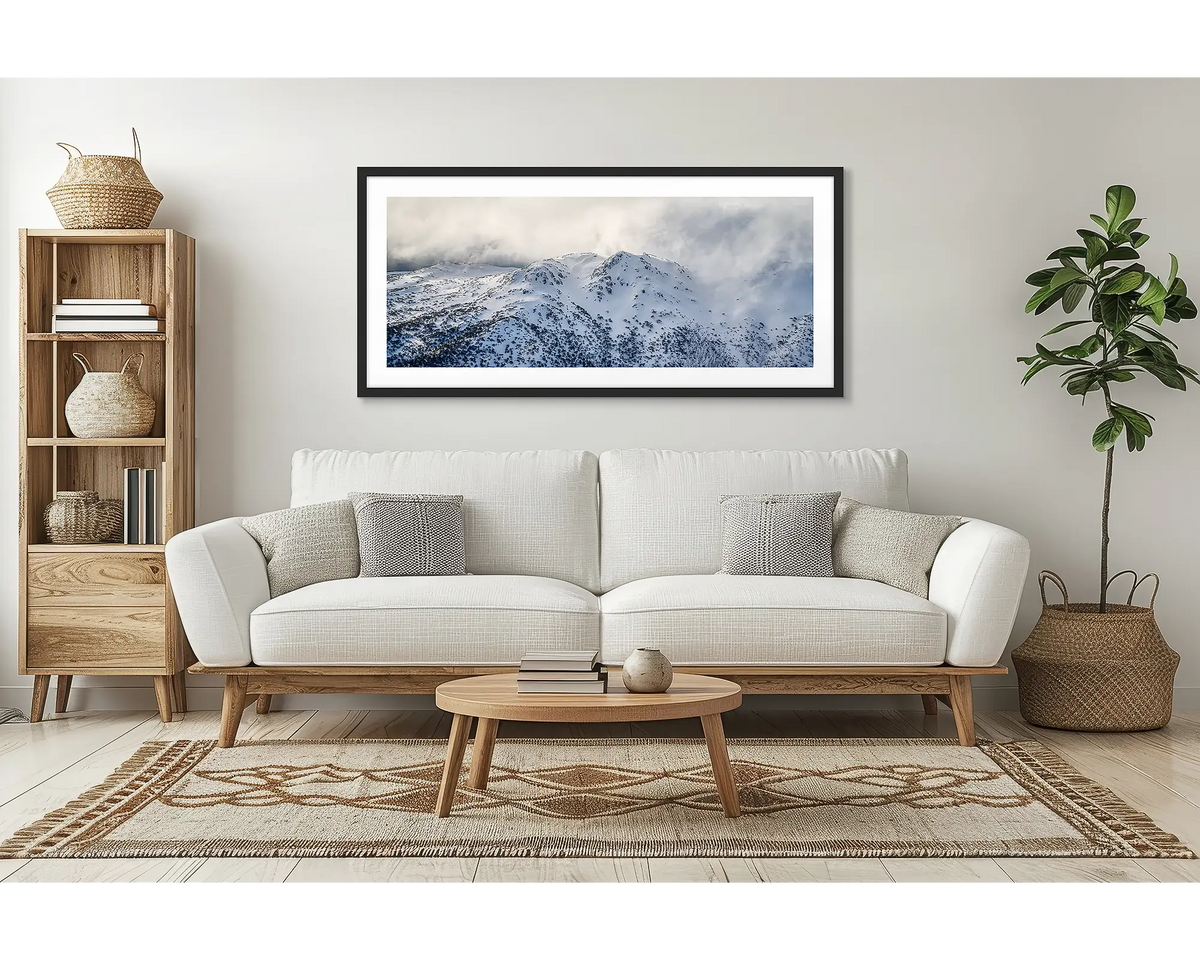 Veil of the Alps. Wall art print of twin humps with fog and snow, framed in a black frame and hung above a lounge room couch. 