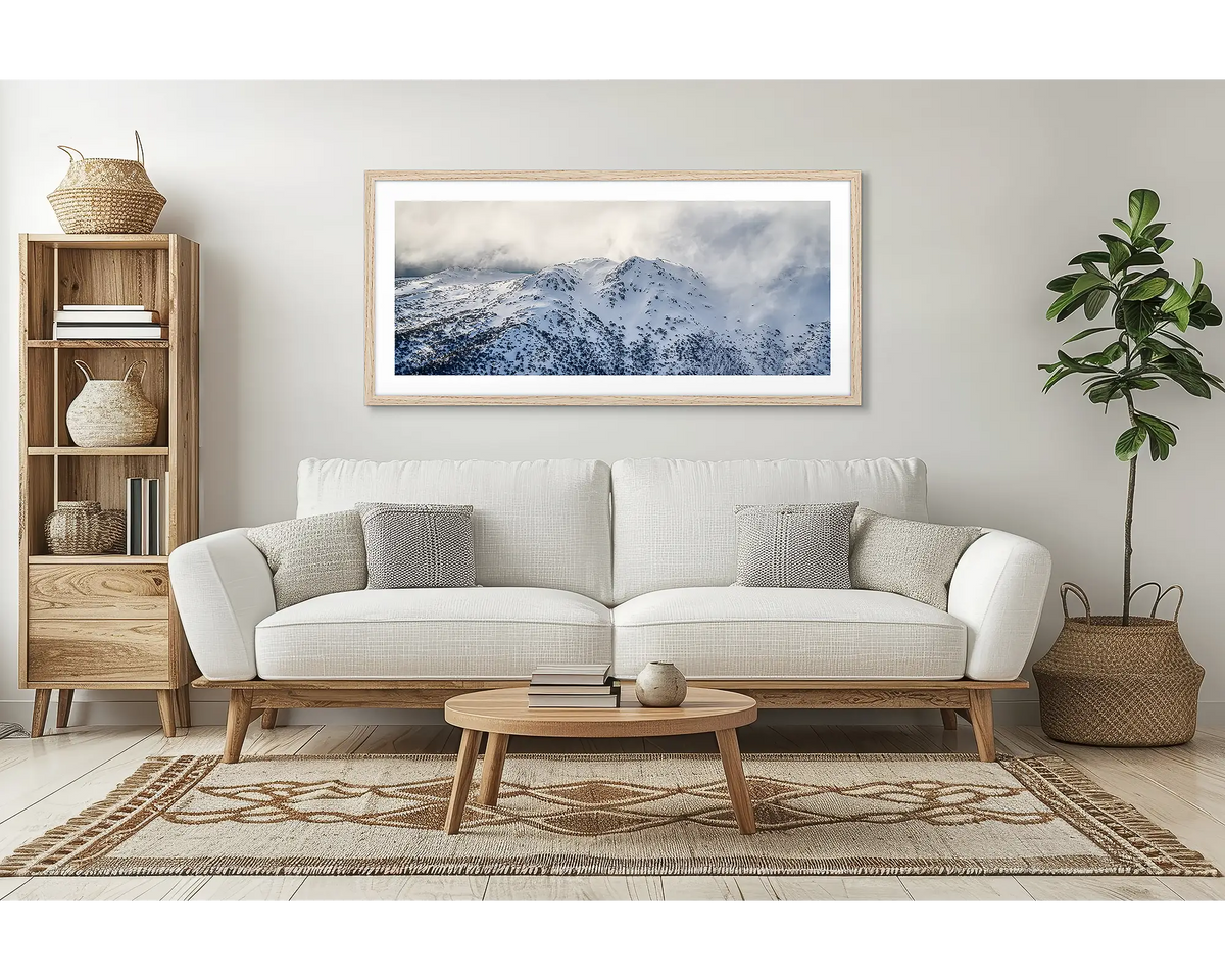 Veil of the Alps. Wall art print of twin humps with fog and snow, framed in a timber frame and hung above a lounge room couch. 