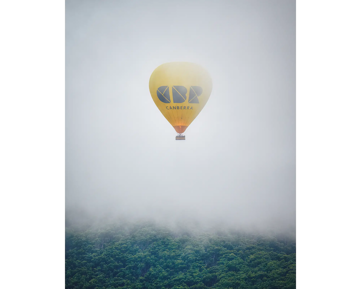 Visit Canberra hot air balloon emerging from fog over Black Mountain during Canberra balloon festival.