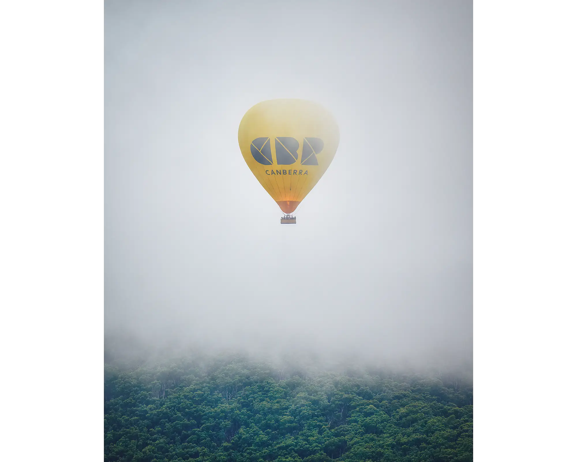 Visit Canberra hot air balloon emerging from fog over Black Mountain during Canberra balloon festival.