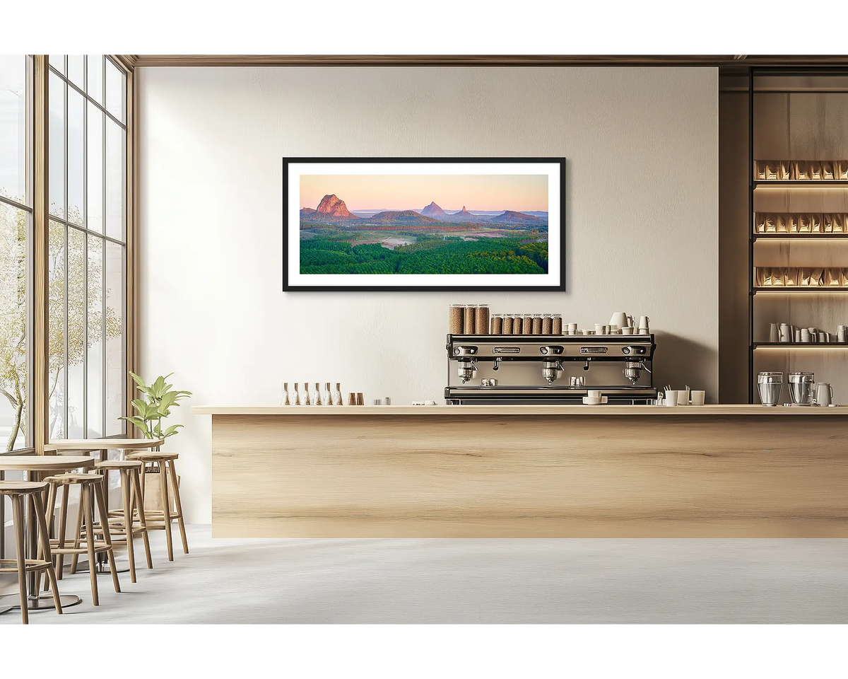 Volcanic Dawn. Glasshouse Mountains wall art print with a black frame hung in a cafe. 
