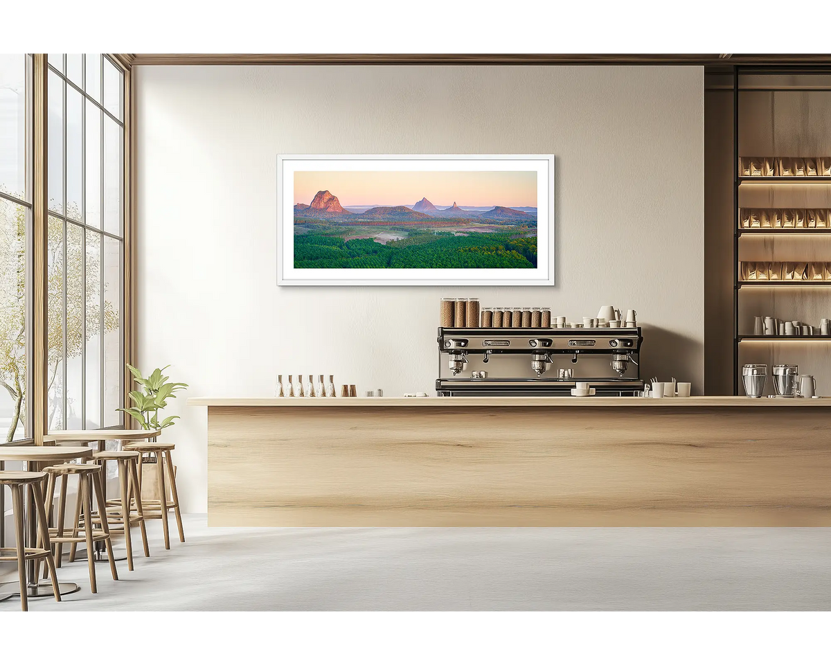 Volcanic Dawn. Glasshouse Mountains wall art print with a white frame hung in a cafe. 
