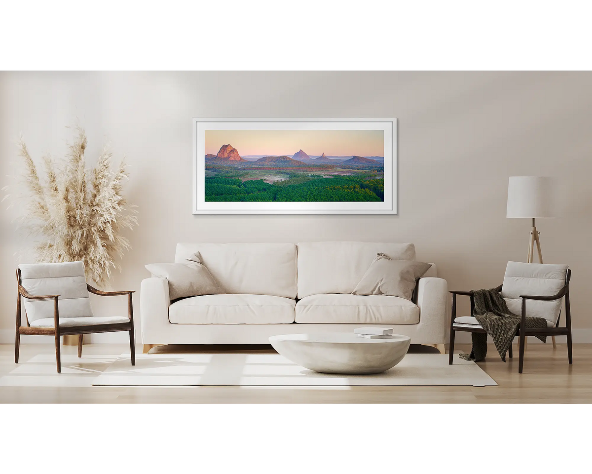 Volcanic Dawn. Wall art print with white frame of Glasshouse Mountains, Queensland, hung above a couch.