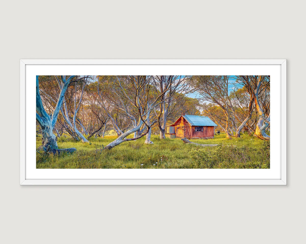 Framed photograph of a rustic JB Hut in the Alpine National Park nestled among trees with a white frame.