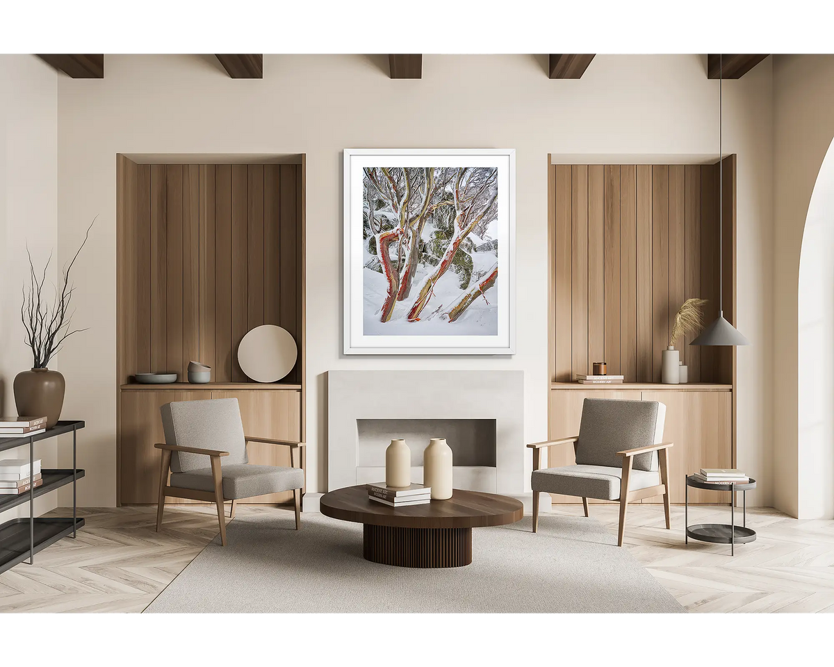 Weathered Reds. Framed wall art print of snow gums with red bark, covered in snow, with a white frame in a modern, scandi inspired apartment. 