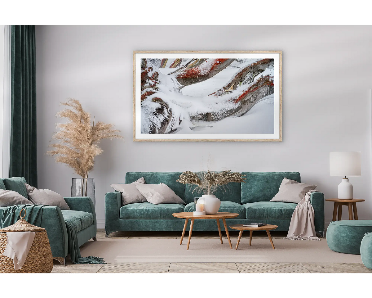 Weight. Framed wall art print of snow gum branches covered in snow, with a timber frame hung in a lounge room. 