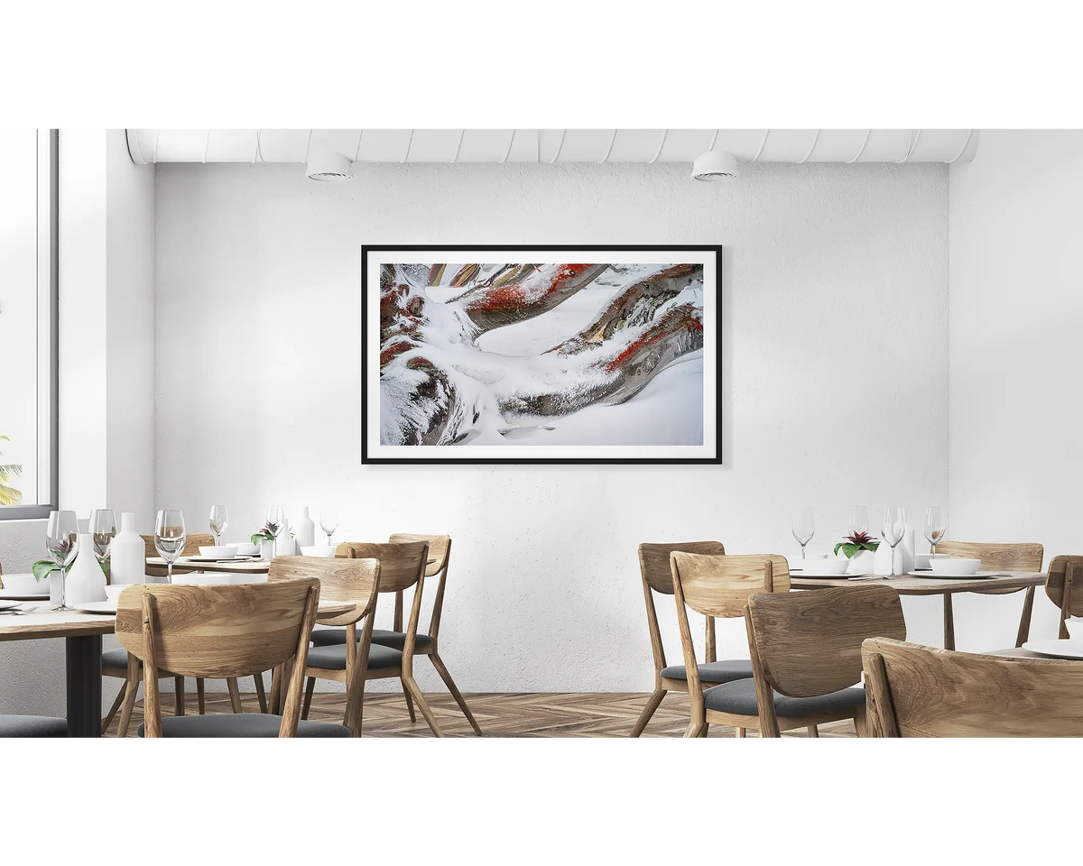 Weight. Wall art print of snow covered snow gum branches framed in a black frame and hung above a couch.