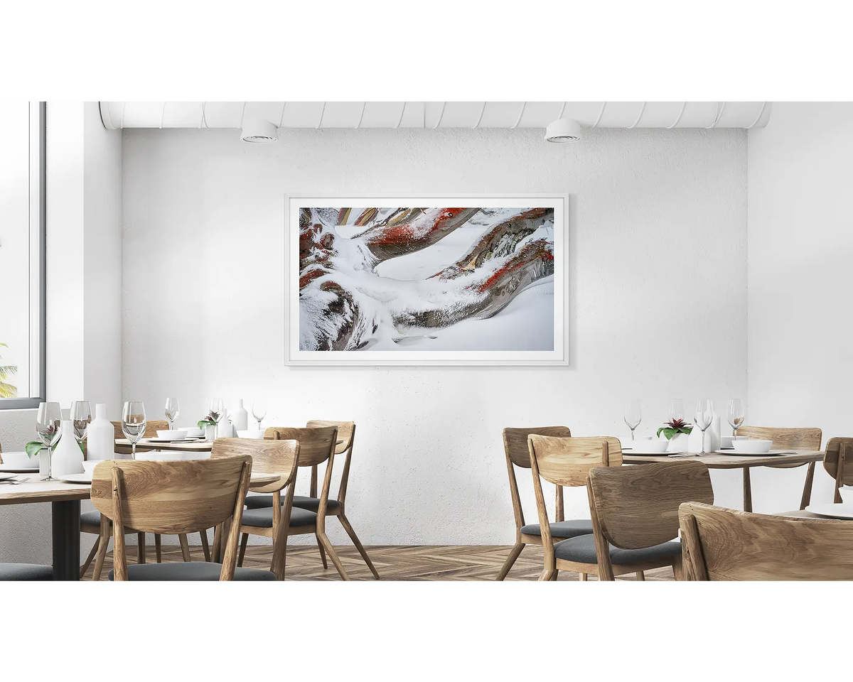 Weight. Wall art print of snow covered snow gum branches framed in a white frame and hung in a cafe. 