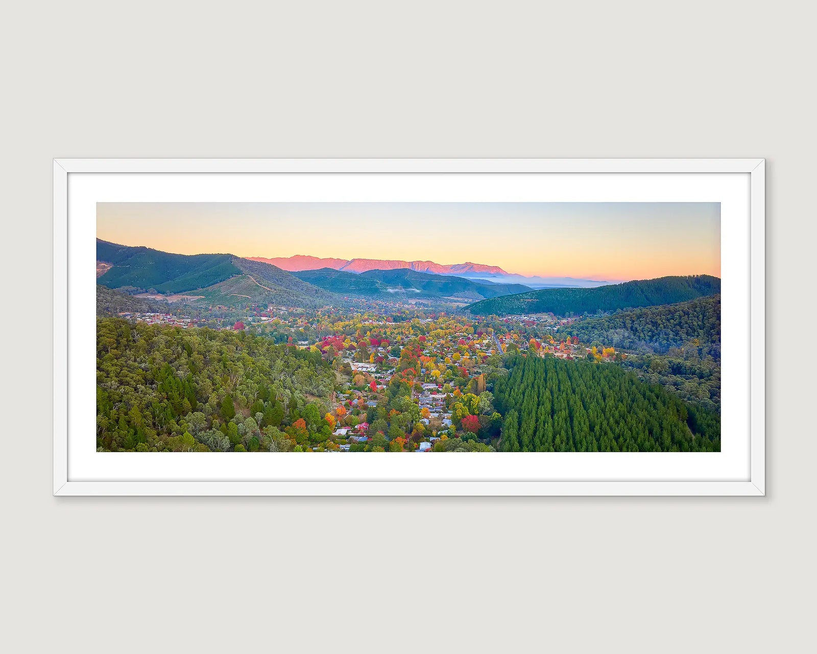 Framed panoramic landscape of the town of Bright, Victoria with mountains and trees at sunset.