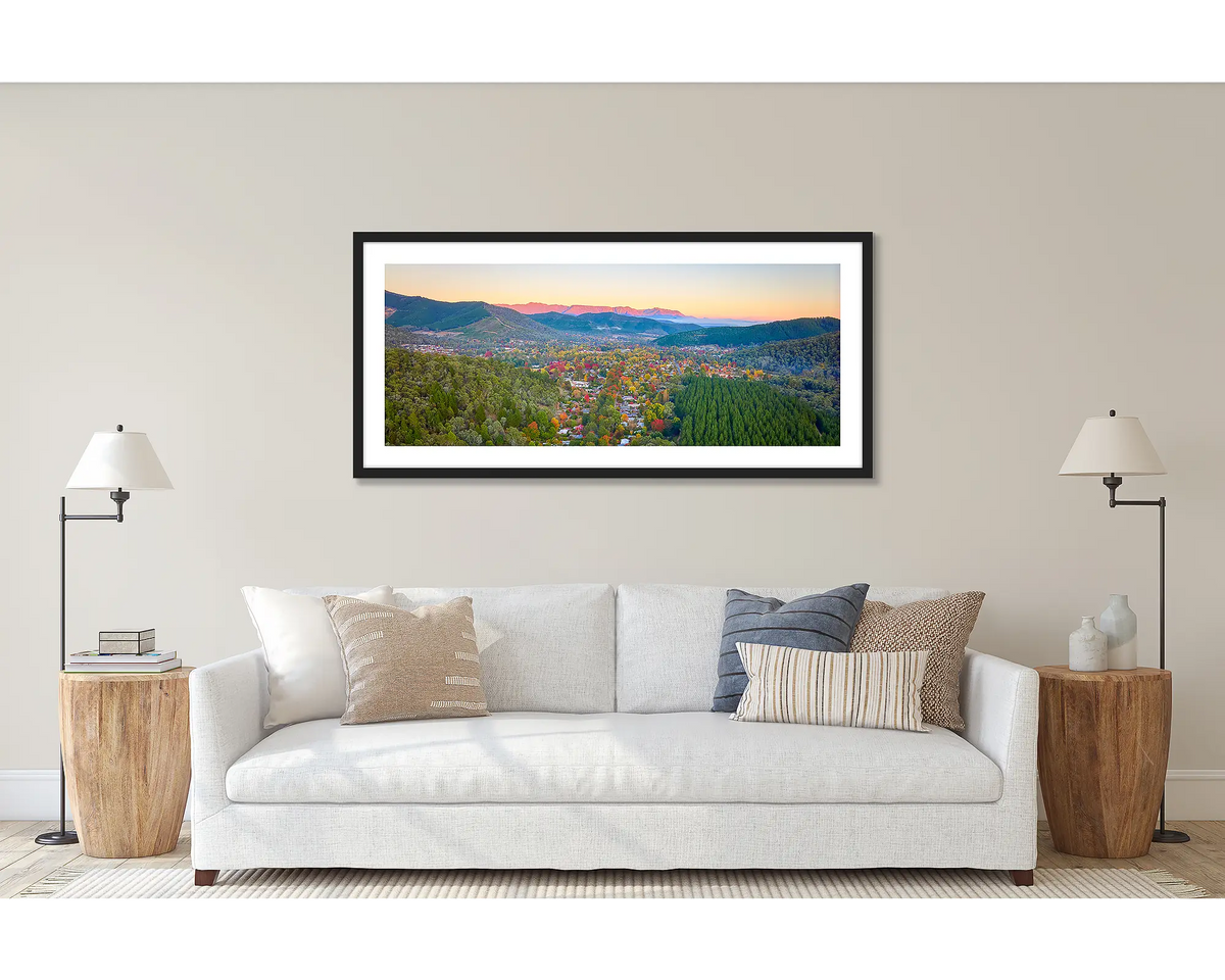 Welcome to Bright. Wall art print of a sunrise over Bright in North-East Victoria, framed in a black frame and hung above a couch. 