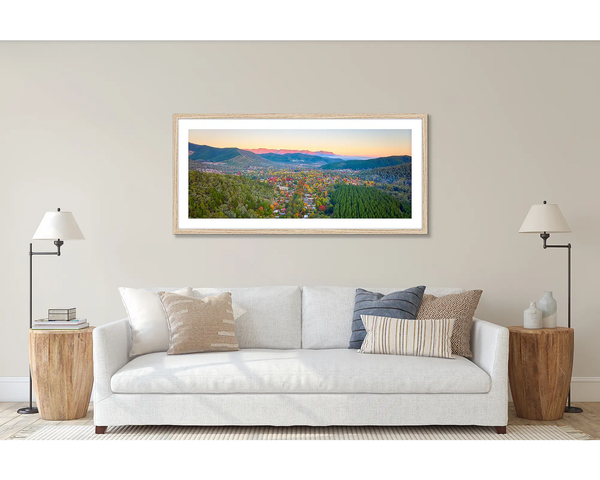 Welcome to Bright. Wall art print of a sunrise over Bright in North-East Victoria, framed in a timber frame and hung above a couch. 