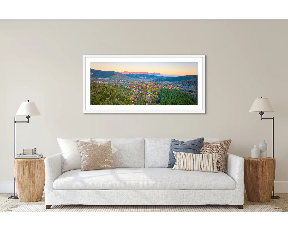 Welcome to Bright. Wall art print of a sunrise over Bright in North-East Victoria, framed in a white frame and hung above a couch. 