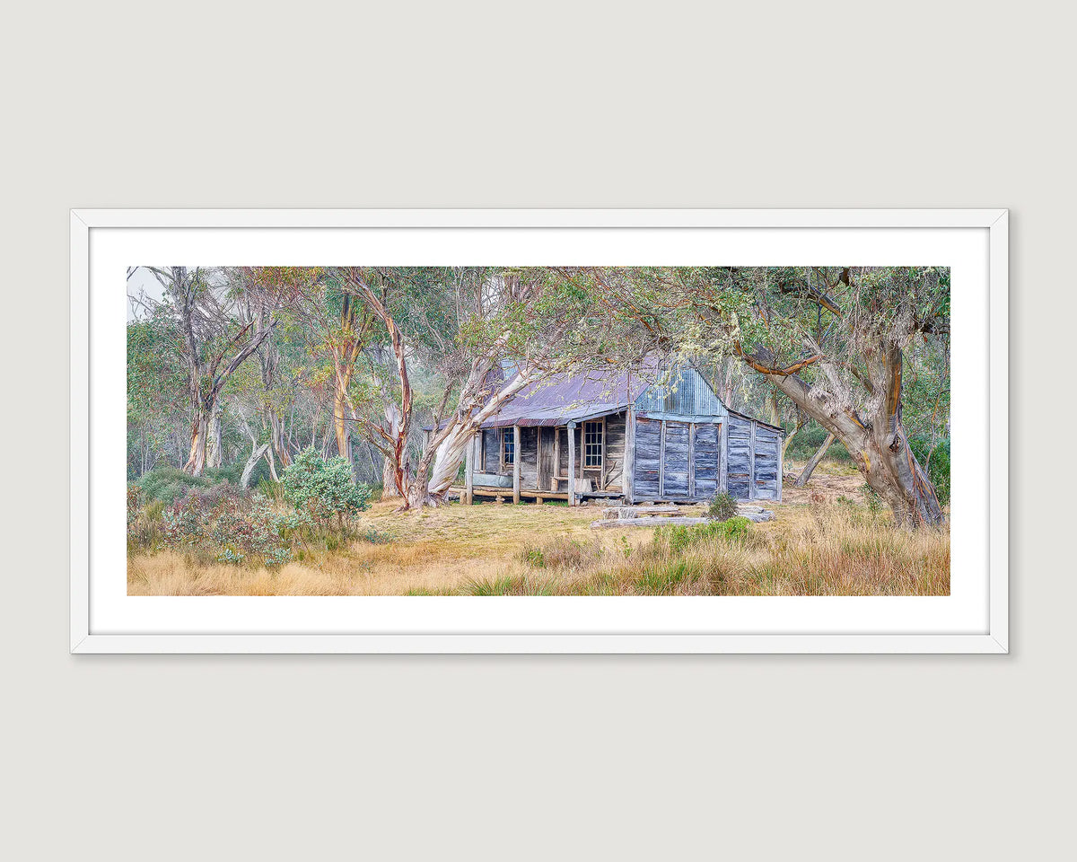 Framed photograph of Wheelers Hut rustic cabin in a forest setting.