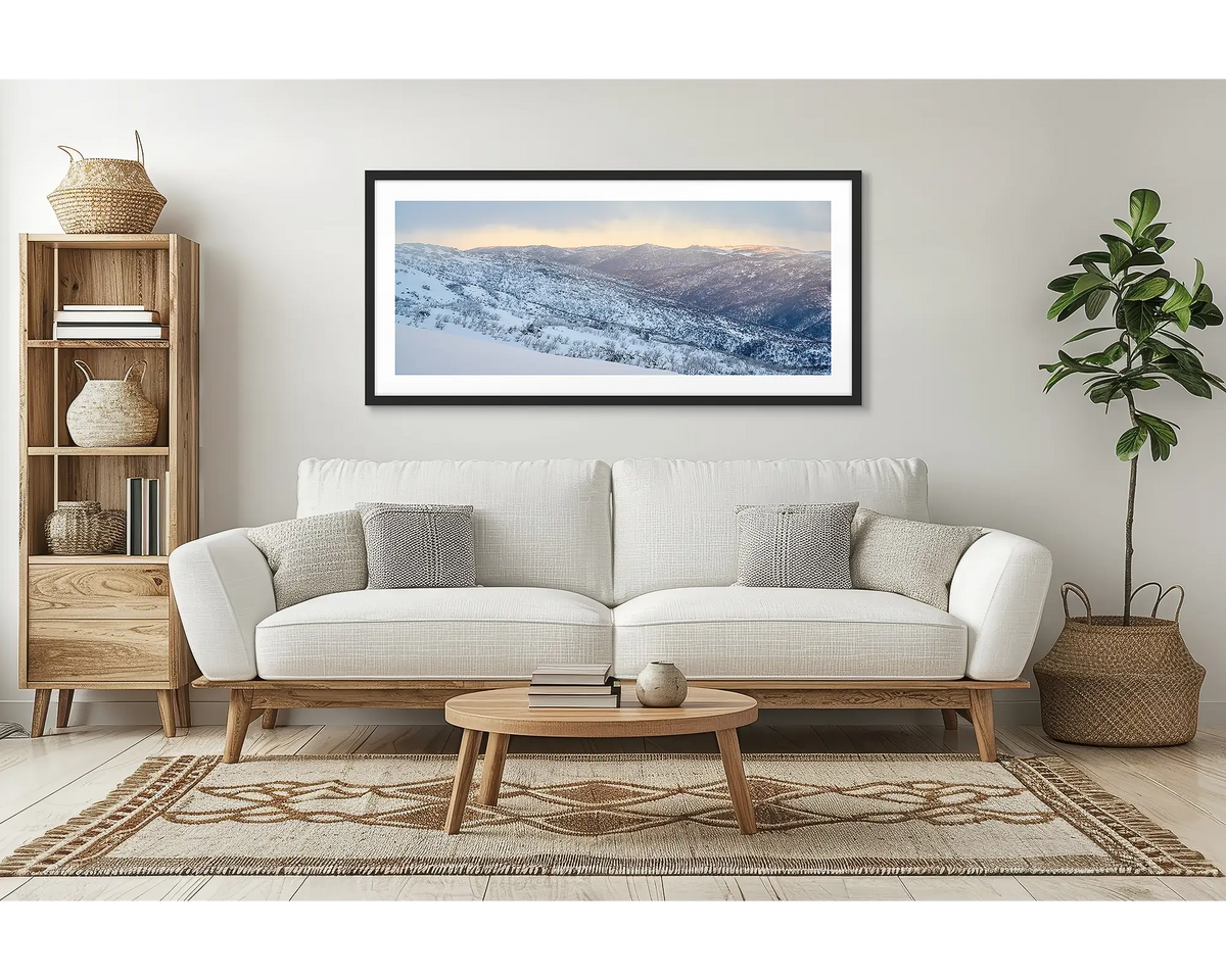 Whispers of Winter. Wall art print of Thredbo Valley covered in snow, framed in a black frame and hung above a lounge room couch. 