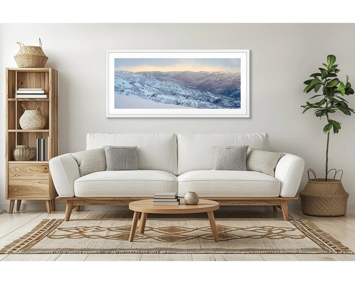 Whispers of Winter. Wall art print of Thredbo Valley covered in snow, framed in a white frame and hung above a lounge room couch. 