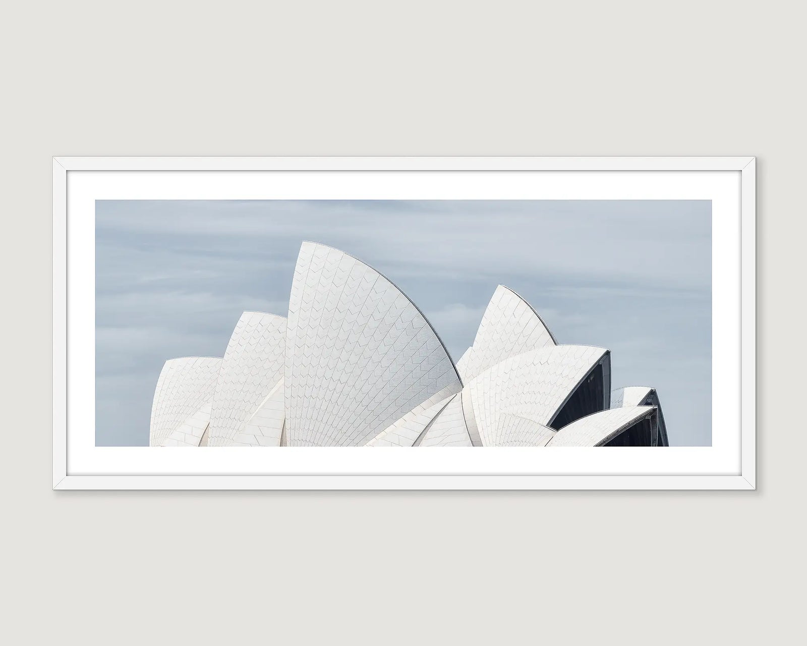 Framed photograph of the Sydney Opera House sails against a light blue sky.
