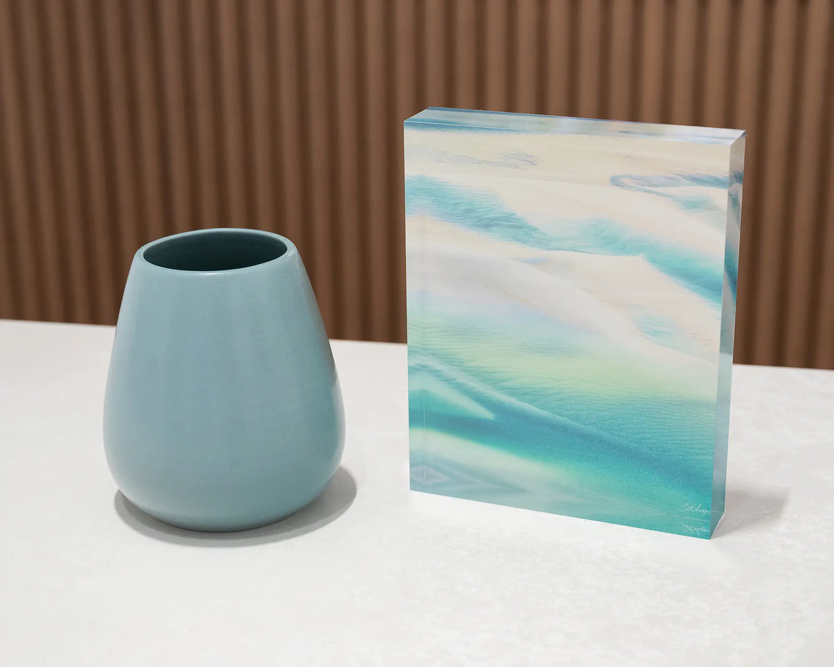 Whitsunday Colours. Acrylic block of an aerial view of Whitsunday Island, Queensland, on a desk styled with a small vase.
