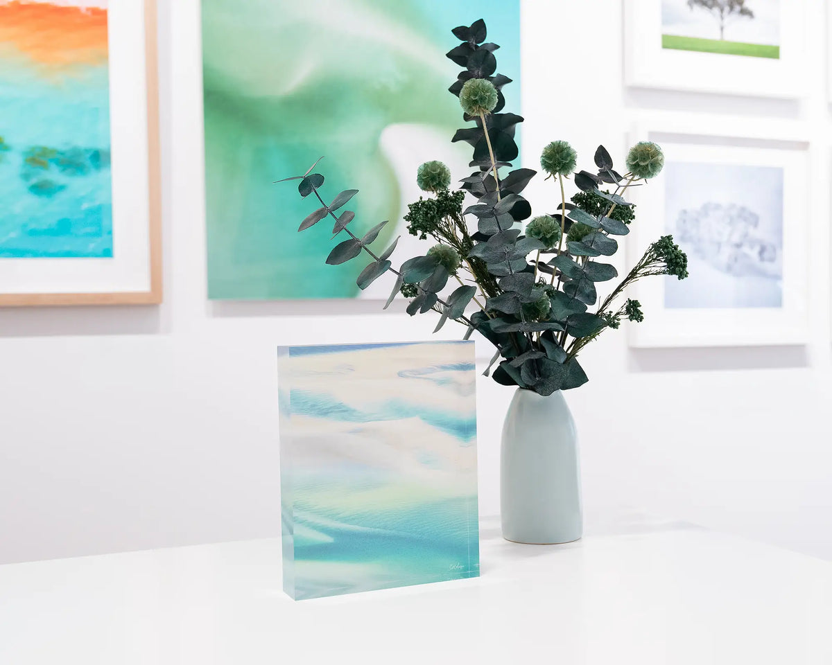 Whitsunday Colours. Acrylic block of an aerial view of Whitsunday Island, Queensland, styled in the gallery with a flower arrangement.