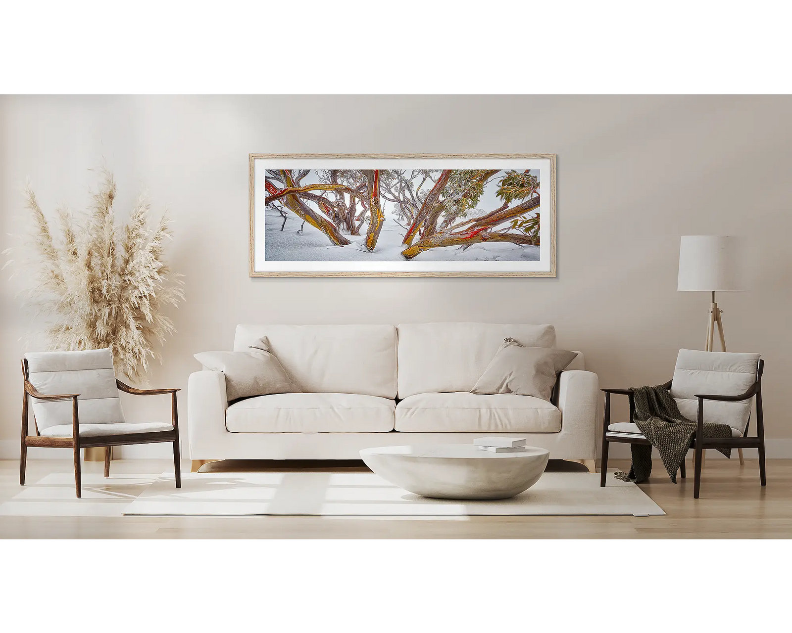 Framed artwork of snow-covered snow gum trees with red-barked trunks on a white wall.