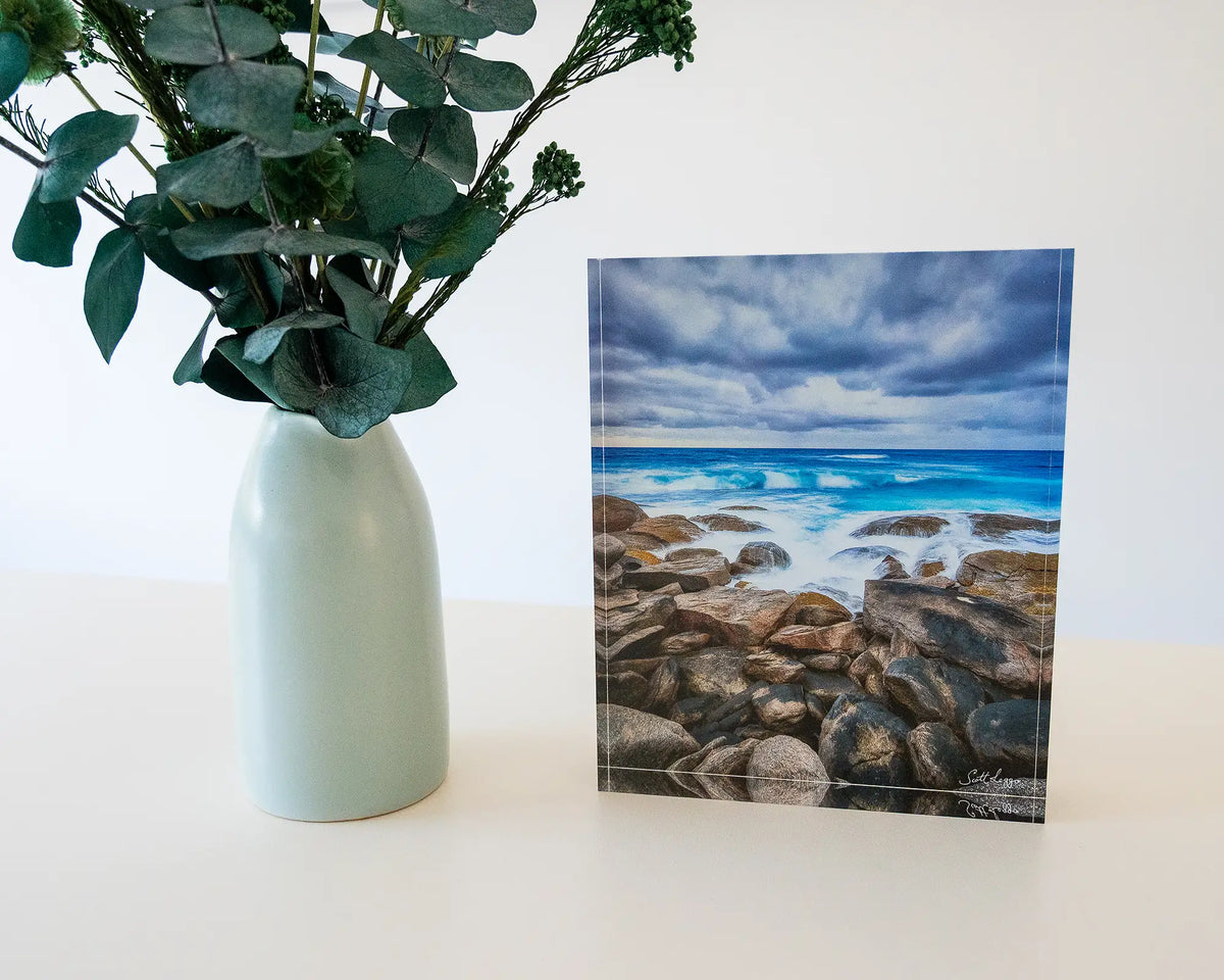 Wild West. Acrylic block of Redgate Leeuwin Naturaliste National Park, Western Australia, on desk with flower vase.