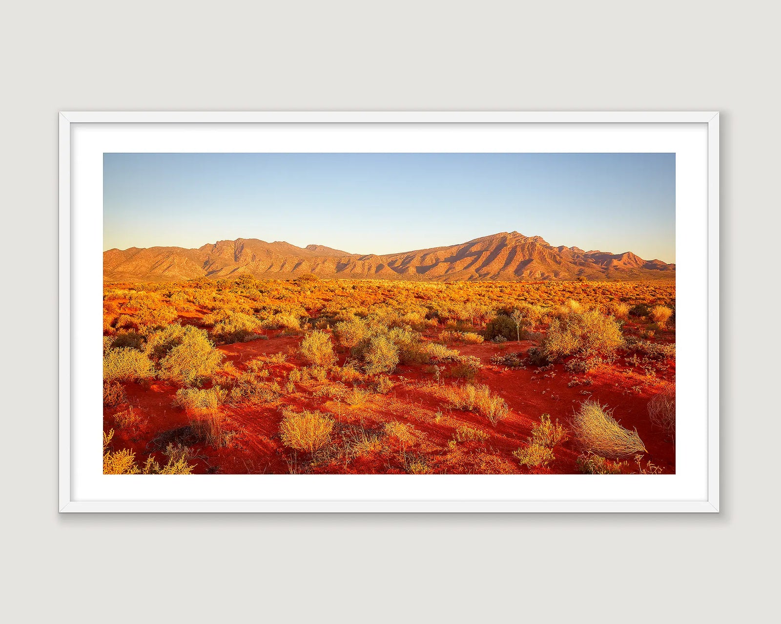 Framed photograph of a mountain range in the desert and a blue sky.
