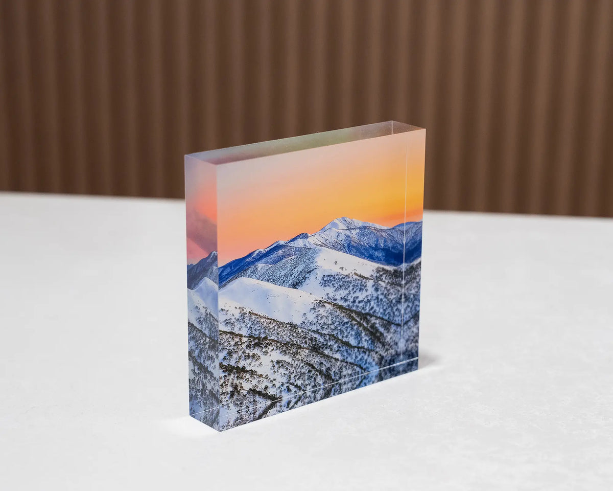 Winter Glow. Acrylic block of an orange sunrise over summit of Mount Feathertop, sitting on a desk.